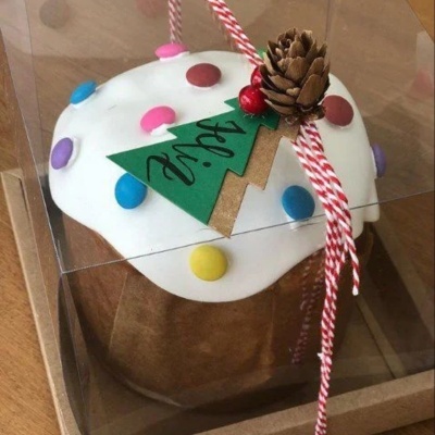 Panetone decorado coberto com glacê branco e confeitos coloridos em embalagem transparente com laço