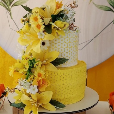 Bolo amarelo com flores artificiais e padrões geométricos