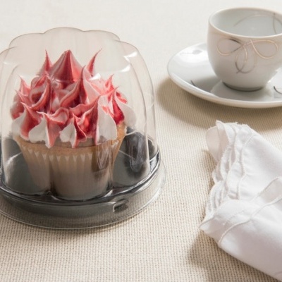 Sobremesa em embalagem plástica com chávena de porcelana e guardanapo branco sobre superfície clara