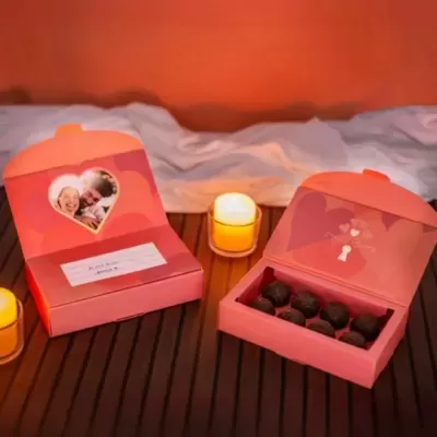 Caixas de bombons rosas com decoração de coração, foto de casal e velas ambiente