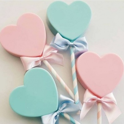 Pirulitos em forma de coração cor-de-rosa e azul claro com fitas de cetim