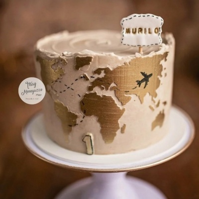 Bolo decorado com mapa mundial dourado e branco com placa MURILO