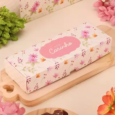 Caixa retangular decorada com flores e texto 'Com Carinho' em etiqueta rosa