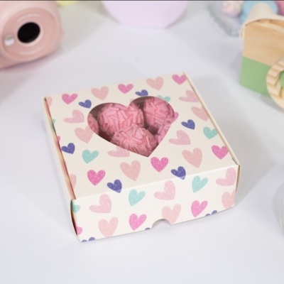 Caixa com cupcakes de cor-de-rosa em caixa com corações coloridos e objetos decorativos em fundo branco