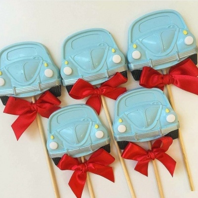 Pirulitos em formato de carrinho azul claro com laços vermelhos