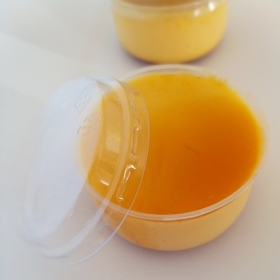 Recipientes plásticos com creme amarelo-laranja e tampa transparente