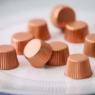 Oito cápsulas de café bronze sobre prato branco