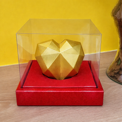 Escultura coração dourado facetado em caixa transparente com base vermelha