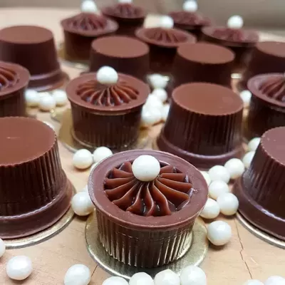 Bombons de chocolate com decoração branca em superfície bege