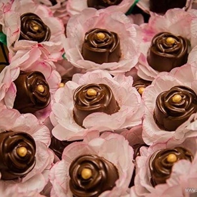 Doces de chocolate em formato de rosa dentro de forminhas rosas que parecem flores