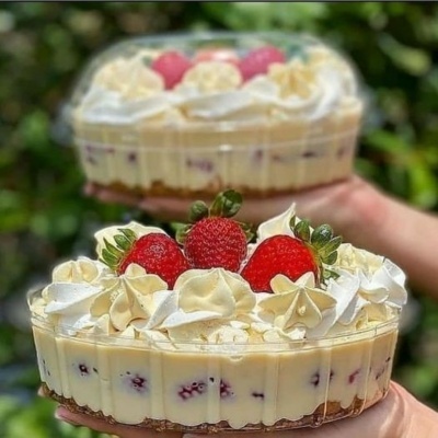 Dois bolos com chantilly e morangos em embalagens transparentes