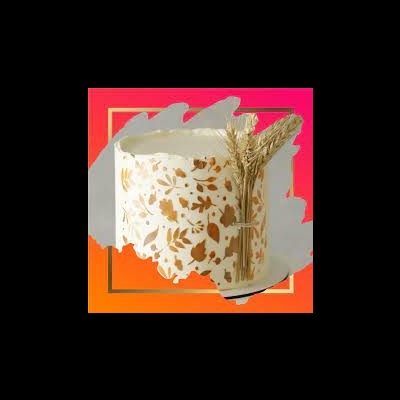 Vela branca com suporte decorado com folhas douradas e raminhos secos.