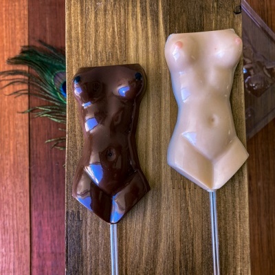 Dois gelados em forma de torso feminino em chocolate escuro e creme sobre tábua de madeira