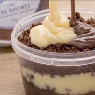 Sobremesa com camadas de creme amarelo, creme castanho e chocolate granulado em recipiente plástico