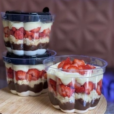 Copos transparentes com sobremesa em camadas de creme, chocolate, biscoito e morangos