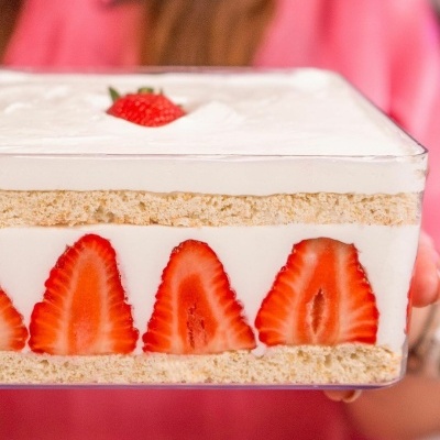Sobremesa em recipiente de vidro com camadas de pão, creme e morangos