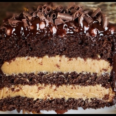 Pedaço de bolo de chocolate com recheio amarelo claro e cobertura de chocolate