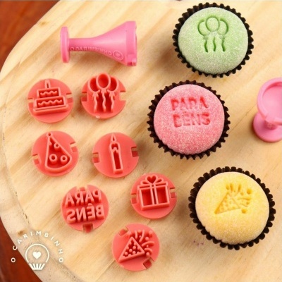 Conjunto de cortadores e carimbos rosa para bolos com vários desenhos e cupcakes coloridos