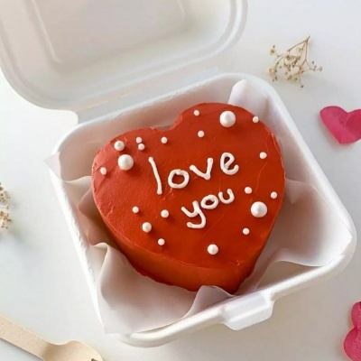 Bolo vermelho em forma de coração com texto 'love you.' em caixa branca