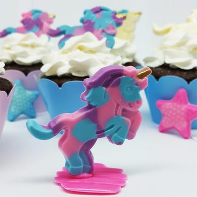 Cupcakes com cobertura branca e toppers de unicórnio coloridos
