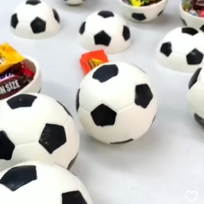 Recipientes em forma de bolas de futebol com doces dentro em superfície branca