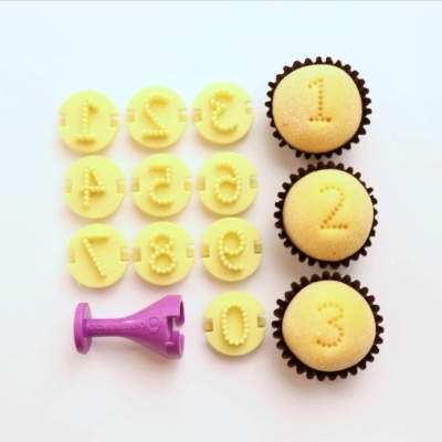 Conjunto de cortantes de números e cupcakes decorados brancos com números em relevo.
