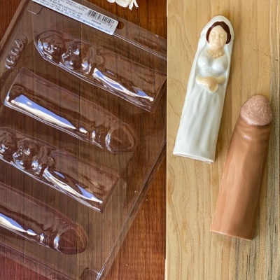 Moldes de silicone para chocolate em forma de pénis e chocolates moldados sobre tábua de madeira decorada.