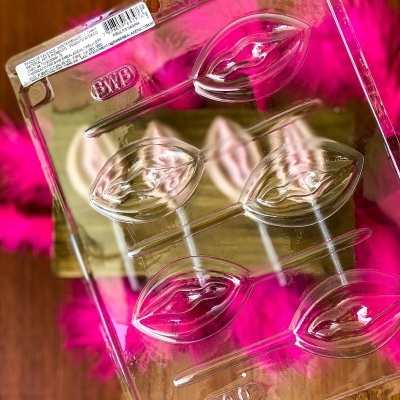 Forma transparente para chocolate em forma de lábios sobre tecido rosa-pink