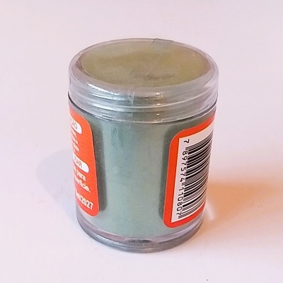 Frasco pequeno de plástico transparente com pó verde e etiquetas laranja