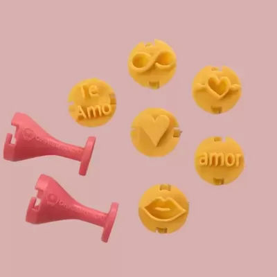 Moldes amarelos com símbolos e textos de amor e peças rosas sobre fundo rosa claro