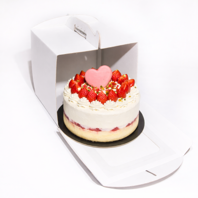 bolo redondo decorado com morangos e chocolate em forma de coração dentro de caixa branca