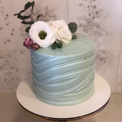 Bolo azul claro com decoração floral natural em suporte branco