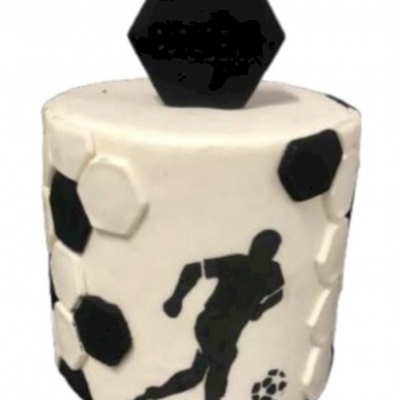 Bolo decorado com tema de futebol, branco com hexágonos pretos e brancos e silhueta de jogador.