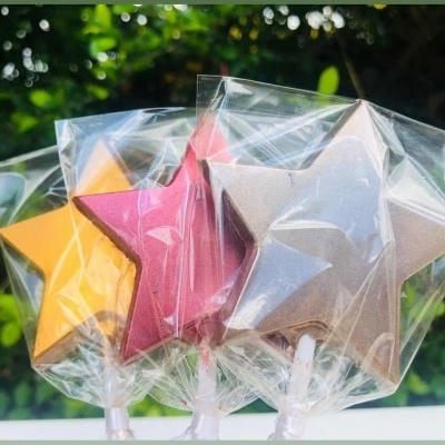 Pirulitos em forma de estrela com cores amarelo, rosa e prateado embalados em plástico