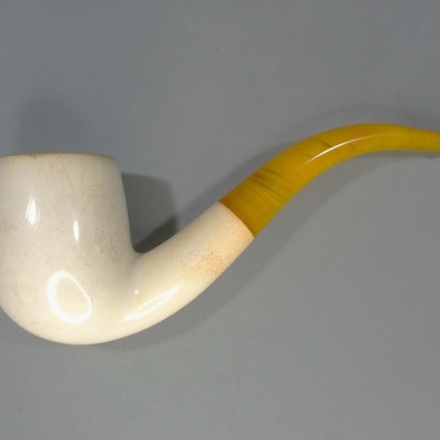 Cachimbo branco com cabo amarelo curvo sobre fundo cinzento