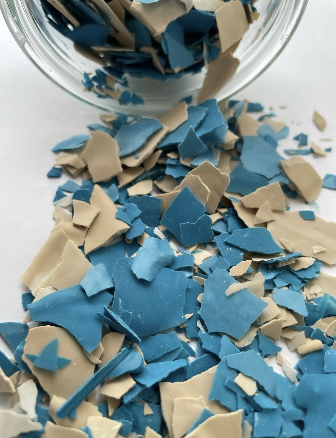 Fragmentos de plástico azul e bege espalhados de um frasco de vidro