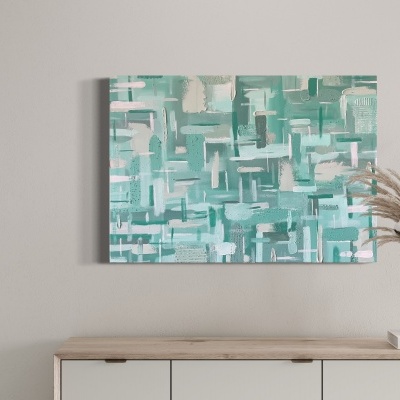 Pintura abstrata verde e azul pendurada numa parede branca sobre um móvel com vaso e copos.