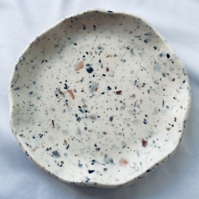 prato cerâmico branco com manchas coloridas sobre tecido branco