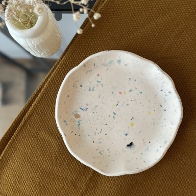 Prato de cerâmica branca com padrão colorido e vaso branco com flores secas