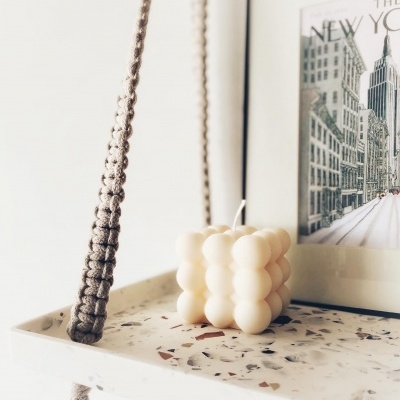 Vela creme em forma de cubo de bolhas sobre prateleira de pedra com padrão terrazzo, corda trançada e moldura com imagem de Nova Iorque
