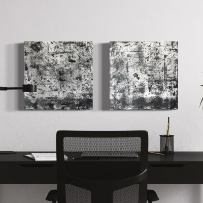 Espaço de trabalho com secretária preta, cadeira, candeeiro, pinturas abstratas cinza e planta verde