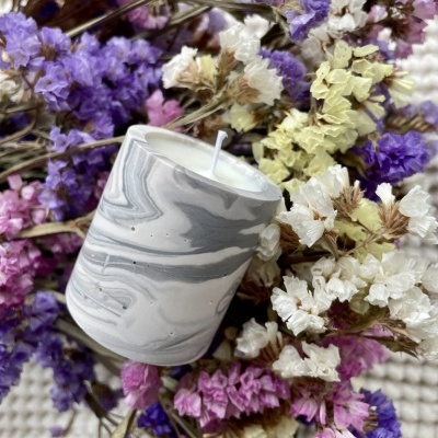 Vela branca em padrão mármore sobre flores secas coloridas