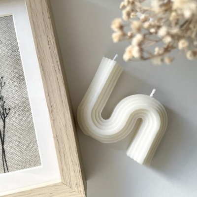 Vela branca em forma de onda com textura estriada junto a moldura e flores secas