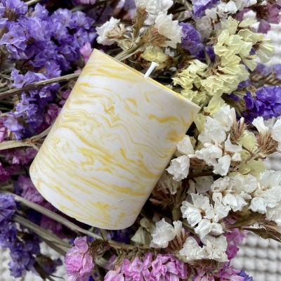 vela marmoreada amarela rodeada por flores secas coloridas