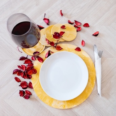 Conjunto de louça amarelo e branco com vinho tinto e pétalas secas vermelhas