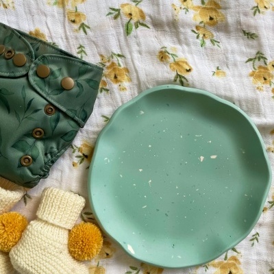 Prato verde claro com textura, tecido floral e acessórios infantis