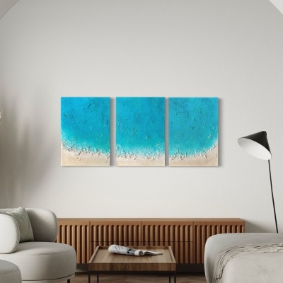 Sala de estar moderna com sofá e poltronas bege, mesa de centro, candeeiro de pé e três painéis azuis e areia na parede.