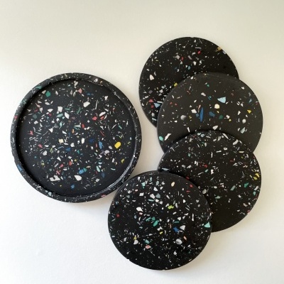 Bases para copos e bandeja redondas pretas com textura colorida sobre fundo branco