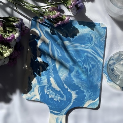 Tabuleiro azul e branco marmoreado com flores secas e copo com gelo