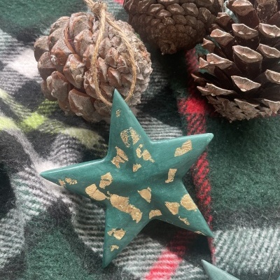 Pinhões naturais e estrela decorativa verde com dourado sobre tecido xadrez.